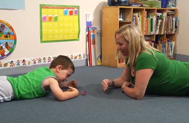 Kim Cunningham on the floor working with young boy