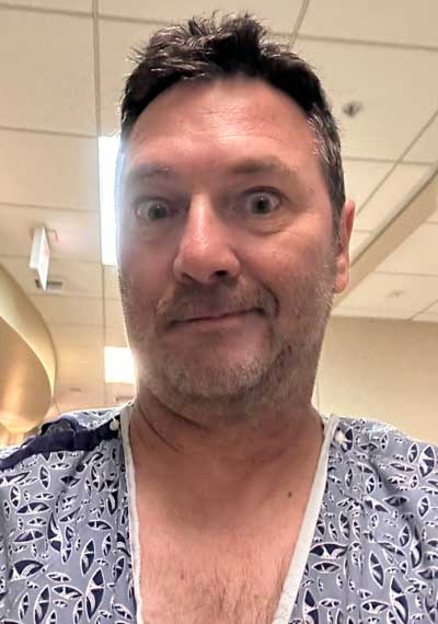 Paul in hospital gown with a puzzling expression