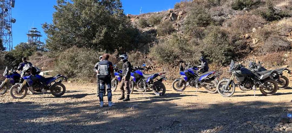 Paul with a group of Yamaha offroad riders parked, taking a break from the ride, dirt hills in background