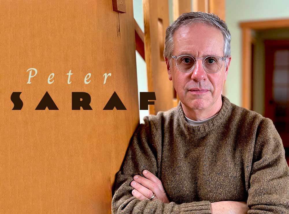 Peter Saraf - man with crossed arms leaning against a wooden wall
