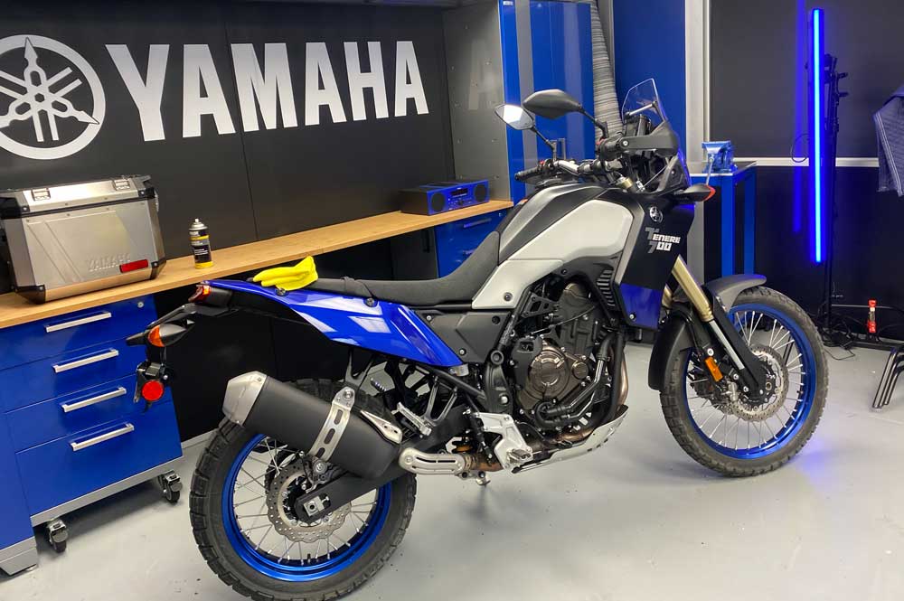 Blue motorcycle with Yamaha on the wall in background