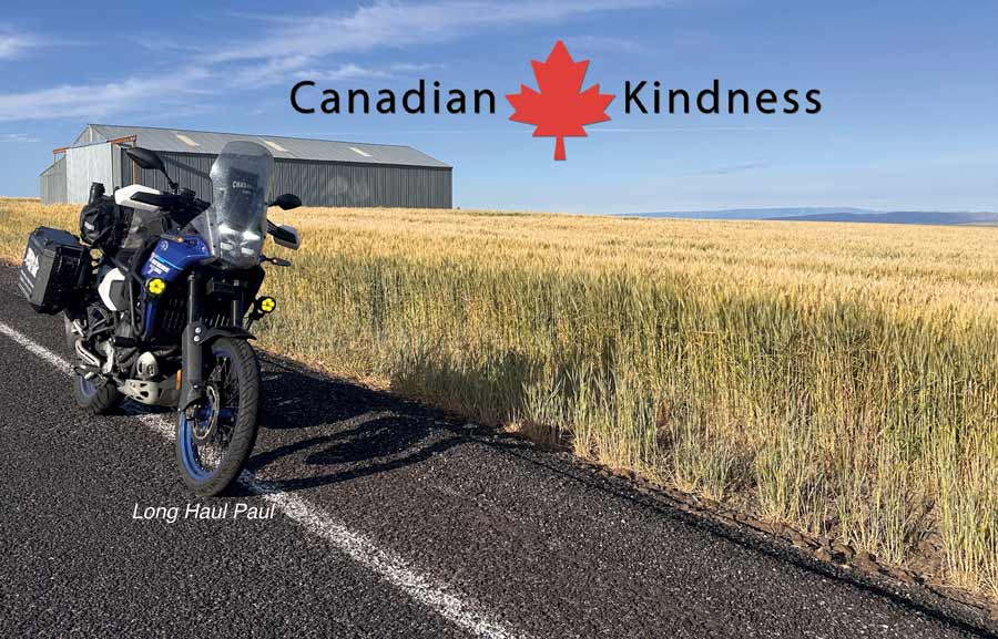 Motorcycle parked on rural road near wheat field with farm building in background, scenic outdoor landscape in Canada