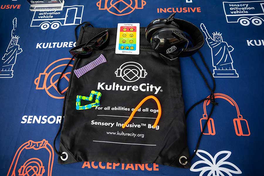 a stuff bag labeled kulture city with dark glasses ear protectors and tactile objects