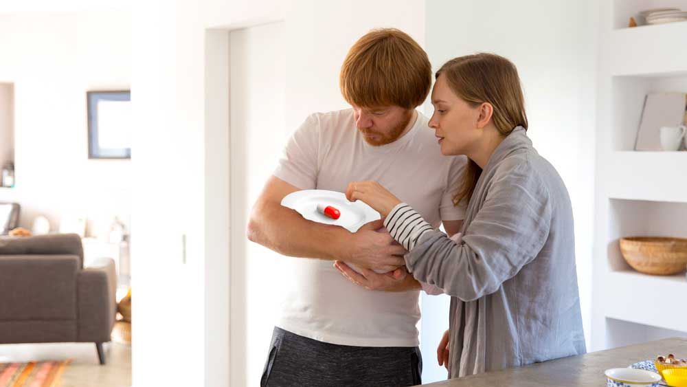 Father swaddles a baby that looks like a large tylenol capsule with mother attentive and assisting