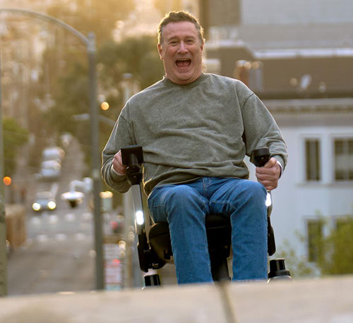 man driving the strutt mobility device up a steep hill on a street in san francisco