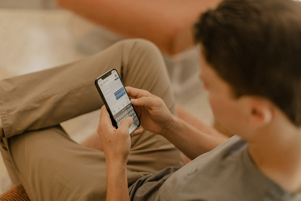 man sitting cross legged typing on a mobile phone