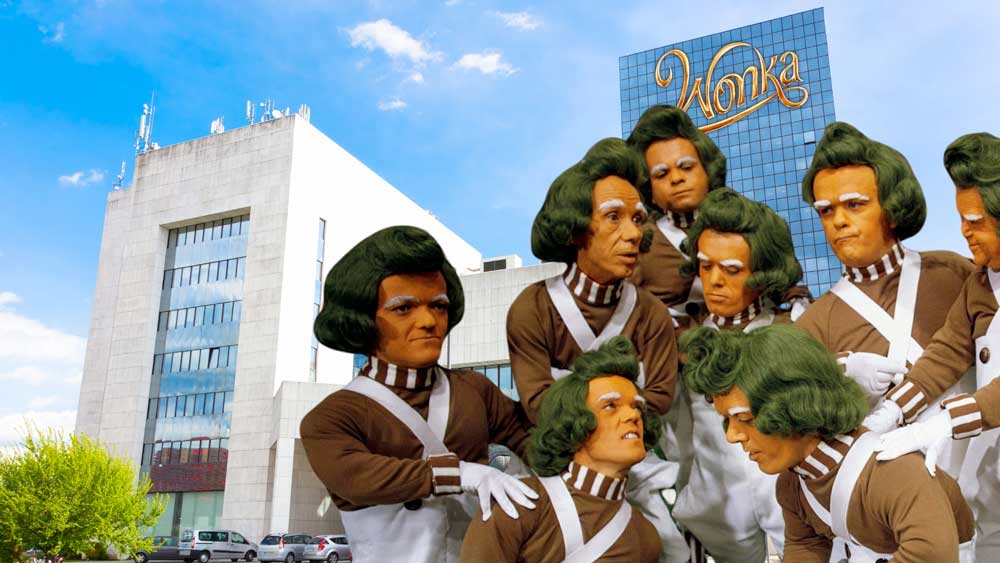 little orange men with green hair and matching brown and white uniforms stand together in front of a high glass office building with a Wonka Sign