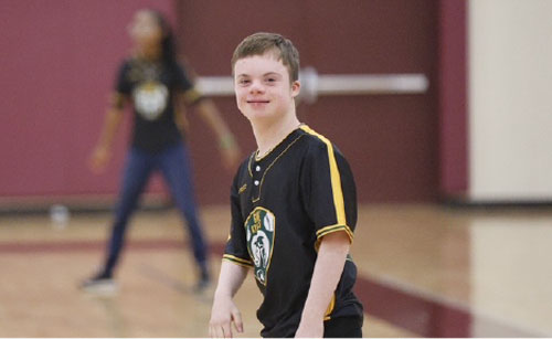 boy in sports shirt stands in gymnasium looking into the camera with a big smile
