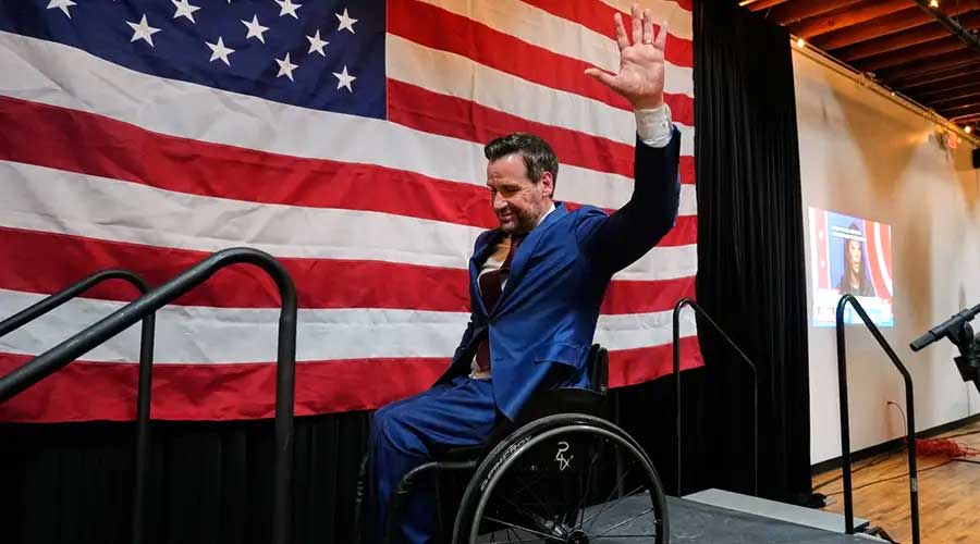 josh turek wheeling off stage with the american flag in the background waving to the audience after his victory