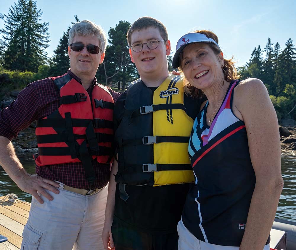 Middle aged man, young man and middle aged woman wear life vests and summer attire outdoors